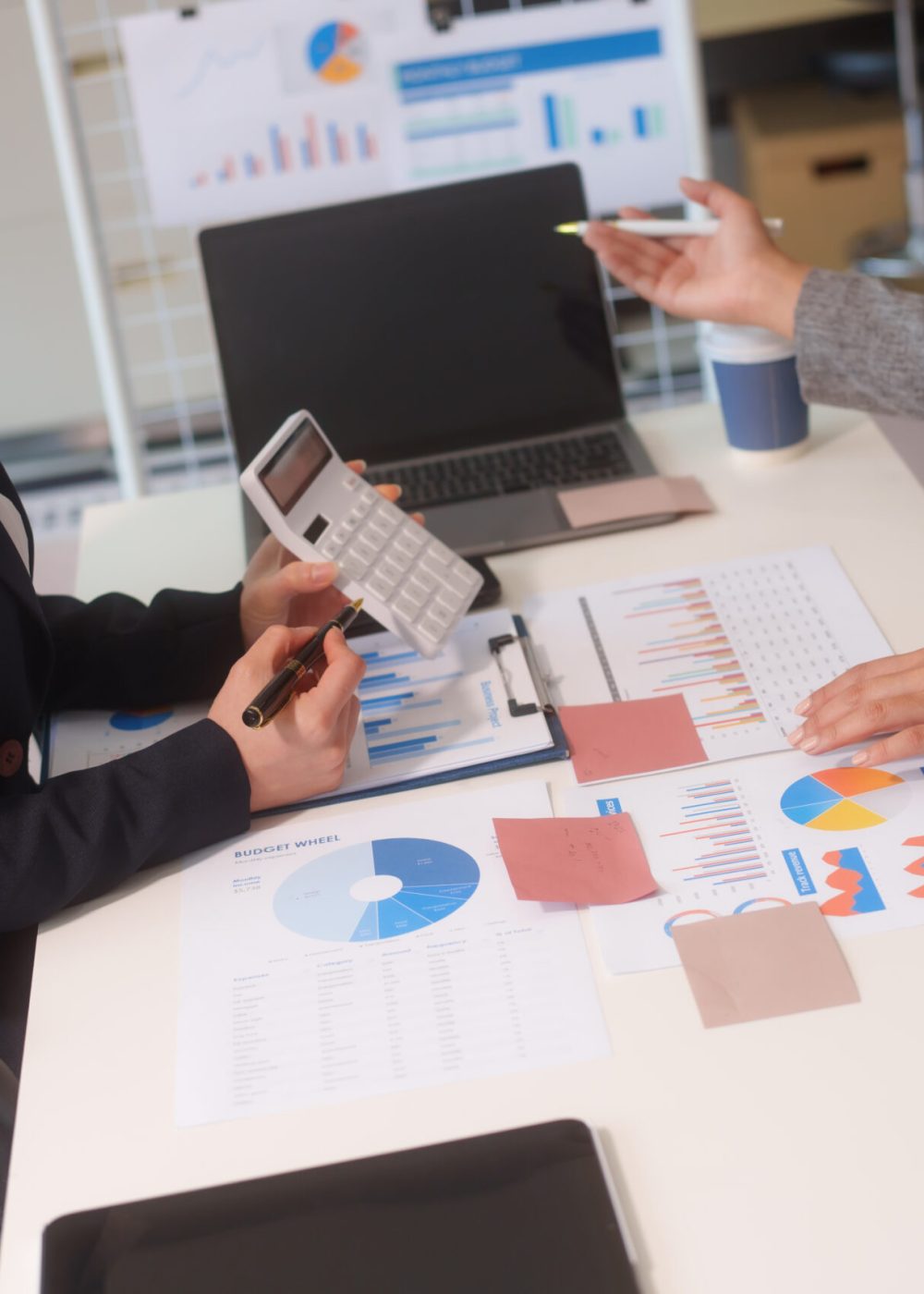 Close-up of two businesswomen working at desk discussing business strategies, analyzing financial